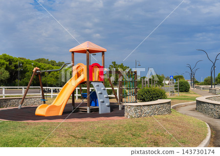 Empty children's playground with yellow slide in seaside park Empty children's playground with yellow slide in seaside park 143730174