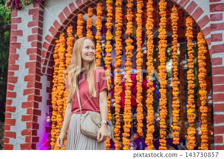 Woman visiting a brick arch decorated with marigold garlands. Woman visiting a brick arch decorated with marigold garlands. 143730857