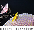 A pink fan, a black background, mizuhiki (decorative cord), and an origami crane. 143731446