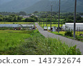 山脈環繞的鄉村景色，溫室和蜿蜒穿過田野的農場道路。 143732674