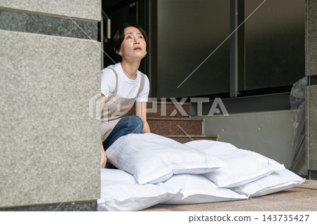 女子正在裝沙袋 女子正在裝沙袋 143735427