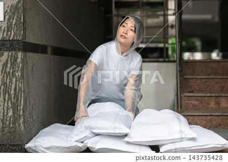 女子正在裝沙袋 女子正在裝沙袋 143735428