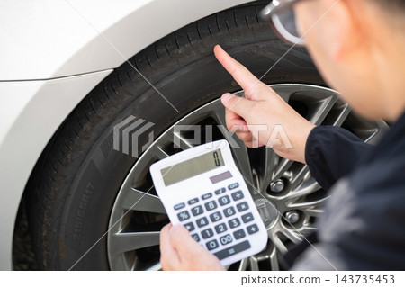 一名男子正在檢查汽車輪胎 一名男子正在檢查汽車輪胎 143735453