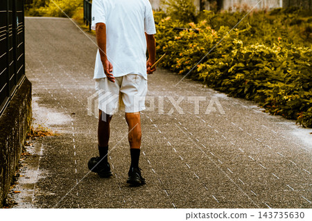 一位穿著短褲的老者背對著鏡頭，沿著郊區的河邊行走。 143735630