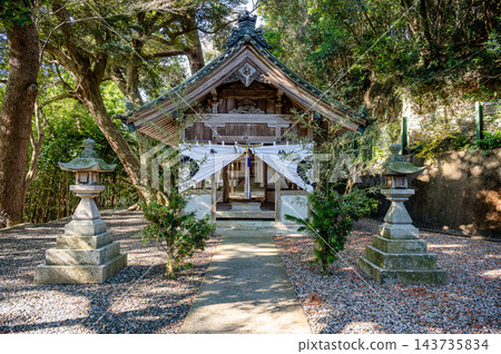 一幅傳統的日本神社景象徐徐展開，周圍環繞著鬱鬱蔥蔥的森林，有木製神社建築、石燈籠、白色帷幔遮蔽的入口和瓦片屋頂。 143735834