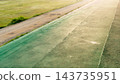 Aerial view of an empty green football stadium field with benches and open space under bright daylight conditions. Running track with green grass in the park sport and recreation concept. 143735951