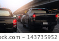 Rear view of pickup truck driving slowly on asphalt road. Heavy traffic on the road with many car stop by red light control. Raised concrete structures flanking the intersection. 143735952