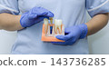 Professional dentist in scrubs holding educational jaw model showing artificial tooth implant restoration process. 143736285