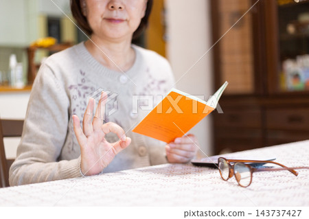 中老年婦女看著她們的橘色退休金手冊，做了一個畫圈的手勢。 143737427