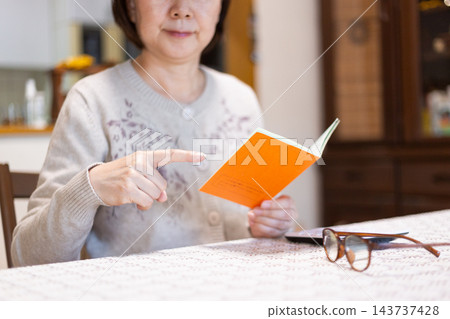 中老年婦女正在查看她們的橙色退休金手冊。 中老年婦女正在查看她們的橙色退休金手冊。 143737428