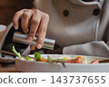 a person using a stainless steel one-handed push-action salt or pepper grinder 143737655