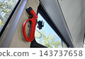 Red emergency hammer mounted beside a vehicle window during daylight 143737658