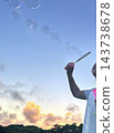 Children blowing soap bubbles at dusk 143738678