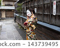 A woman in a kimono with her face hidden by a mask. 143739495