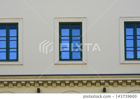 A row of green windows on a minimalistic beige facade A row of green windows on a minimalistic beige facade 143739600