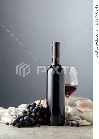 Bottle of red wine with grapes on a grey background. Bottle of red wine with grapes on a grey background. 143740248