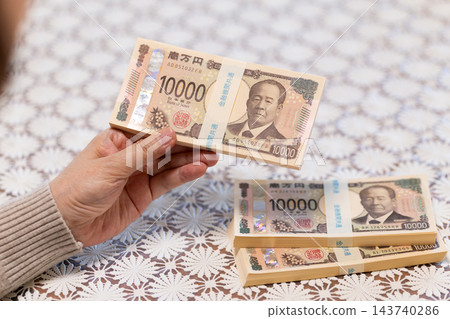中老年婦女手中拿著一疊疊現金 中老年婦女手中拿著一疊疊現金 143740286