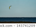 Lonely kitesurfer gliding across wide open sea horizon 143741209