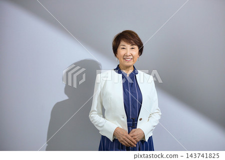 一位六十多歲、穿著外套、笑容燦爛的可愛女士。 143741825