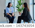 Young woman talking to female psychologist during therapy session in office 143743054