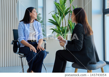 Young woman talking to female psychologist during therapy session in office Young woman talking to female psychologist during therapy session in office 143743054