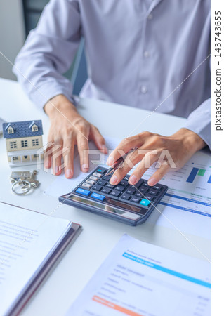 Businessman calculating budget regarding home loan, real estate investment, property tax assessments or mortgage planning. 143743655