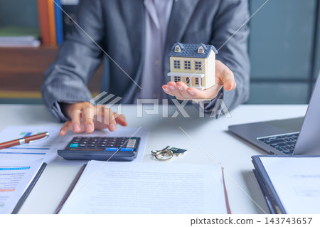 Businessman calculating budget regarding home loan, real estate investment, property tax assessments or mortgage planning. 143743657