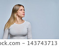 Young blonde woman looking away in studio against gray background shot 143743713