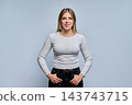 Smiling young female student in casual white sweater on grey background 143743715