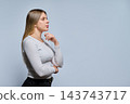 Pensive young woman in profile holding hand to chin with copy space studio shot 143743717