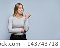 Smiling young woman pointing finger at copy space looking away in shot 143743718