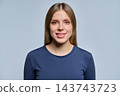 Smiling young woman close up portrait on grey background studio 143743723
