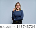Smiling young woman touch hair and looking at camera in studio portrait 143743724