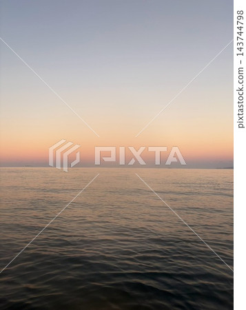 黃昏時分,海面平靜,天空染上了橘色的光芒。 黃昏時分,海面平靜,天空染上了橘色的光芒。 143744798