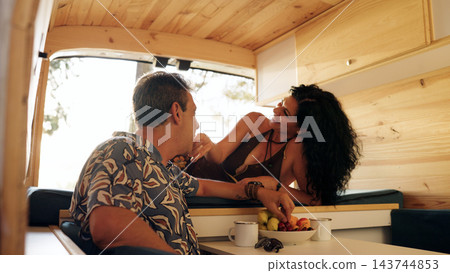 Mature couple enjoying fruits inside camper van Mature couple enjoying fruits inside camper van 143744853
