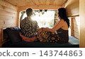 Mature couple relaxing inside camper van enjoying sunset view 143744863