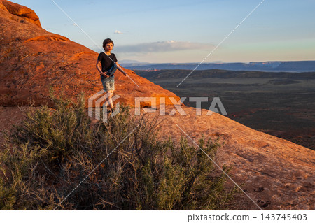 Boy Hiking at Sunset on Devils Garden Trail, Utah Boy Hiking at Sunset on Devils Garden Trail, Utah 143745403
