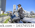 在港未來，一位年輕的女騎士和她心愛的摩托車站在一起。 143745534