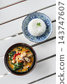 Authentic traditional Tom Yum Talay thai spicy seafood curry soup on white table on outdoor restaurant in Phuket Thailand 143747607