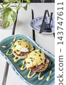 gourmet Eggs Benedict breakfast food on white table at modern restaurant cafe outdoors 143747611