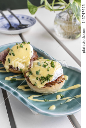 gourmet Eggs Benedict breakfast food on white table at modern restaurant cafe outdoors gourmet Eggs Benedict breakfast food on white table at modern restaurant cafe outdoors 143747613