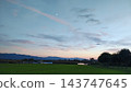 A park scene surrounded by trees and a sky dyed in the colors of the sunset. 143747645