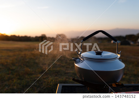 露營地裡,晨光灑滿大地,戶外水壺冒著熱氣。 露營地裡,晨光灑滿大地,戶外水壺冒著熱氣。 143748152