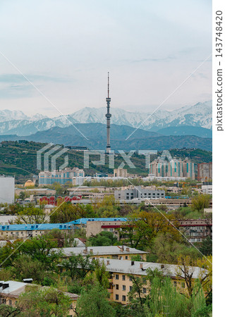 Almaty city skyline with snow capped mountains, red and white TV tower and green spring trees Almaty city skyline with snow capped mountains, red and white TV tower and green spring trees 143748420