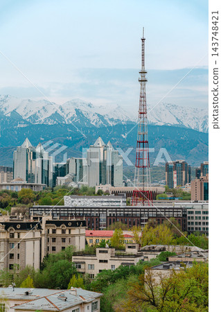 Almaty city skyline with snow capped mountains, red and white TV tower and green spring trees Almaty city skyline with snow capped mountains, red and white TV tower and green spring trees 143748421