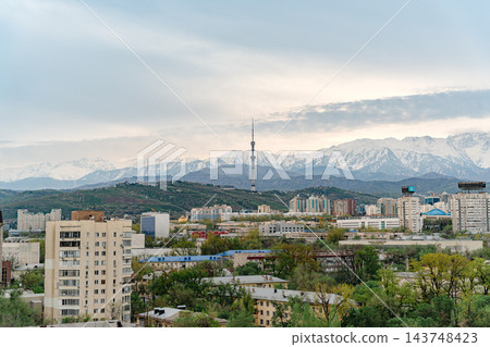 Almaty city skyline with snow capped mountains, red and white TV tower and green spring trees Almaty city skyline with snow capped mountains, red and white TV tower and green spring trees 143748423