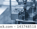 The hole deburring process on metal casting parts using a chamfer tool in a blue tone scene 143748518