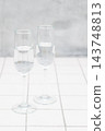 A stylish glass filled with water. A white tiled counter. 143748813