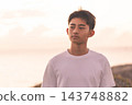 一個男孩凝視著海上的日落。 143748882