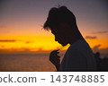夕陽西下，一位年輕男子側臉祈禱。 143748885
